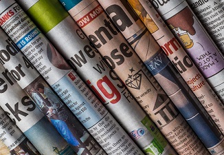 A close-up shot of the folded edges of a stack of newspapers. The folded edges cut diagonally across the image.